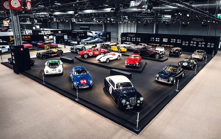 The Lukas Hüni AG stand at Rétromobile Paris 2025, historic sports and racing cars on a dark platform